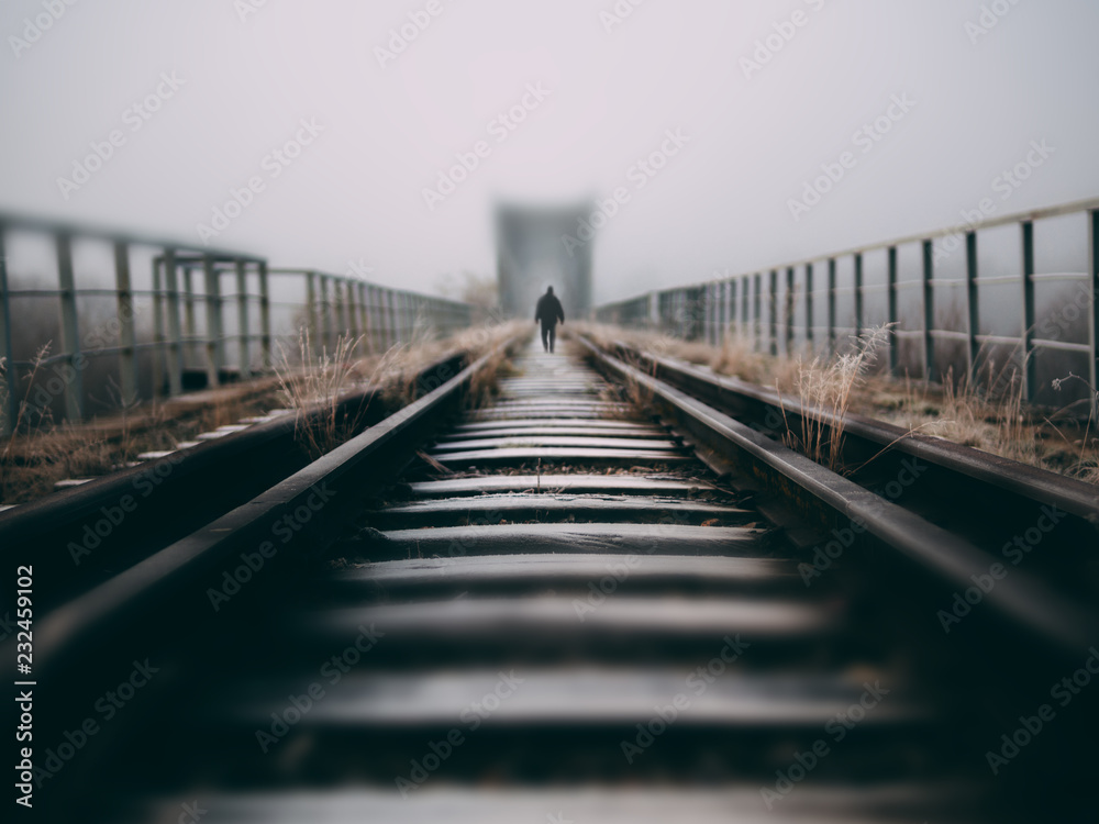Fog on a creepy old bridge with a silhouette of a man in the center