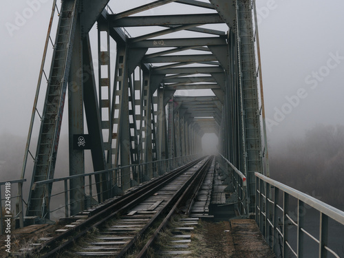 old railway bridge in the early foggy morning. terrible place