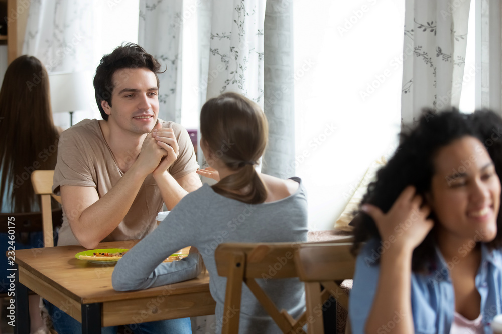 Diverse students young people sitting in row near window talking spending time with soulmates or friends in cozy cafeteria during lunch, focus on caucasian couple. Free time weekend activities concept Diverse students young people sitting in row near window talking spending time with soulmates or friends in cozy cafeteria during lunch, focus on caucasian couple. Free time weekend activities concept