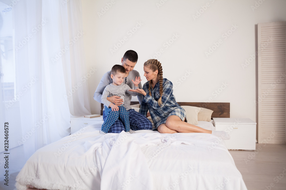 mom dad and son in the morning lying on the bed at home in the morning