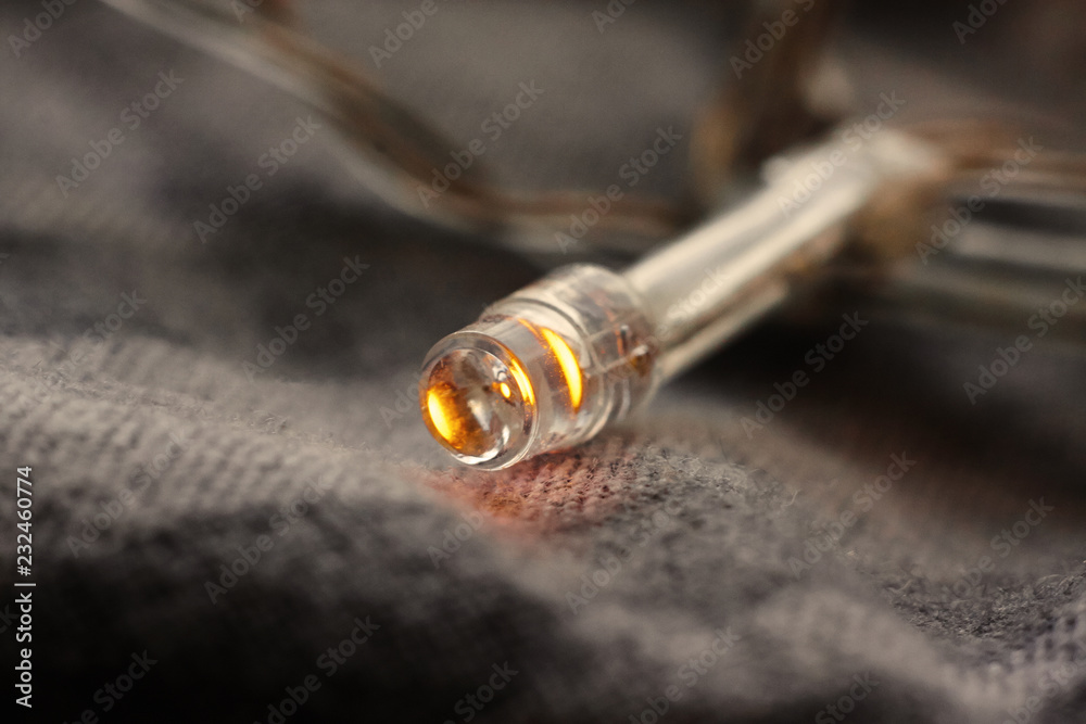 one light bulb garland lies on a grey blanket one light bulb garland lies on a grey blanket