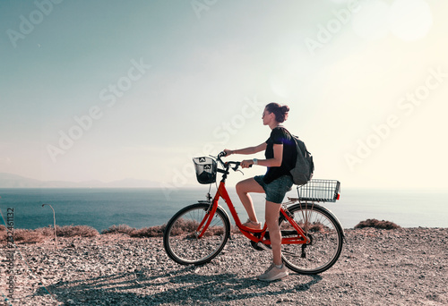 Young beautiful girl woman travels by bicycle on a mountain landscape on the beach in the sun, tourism and leisure concept, Greece, Kos