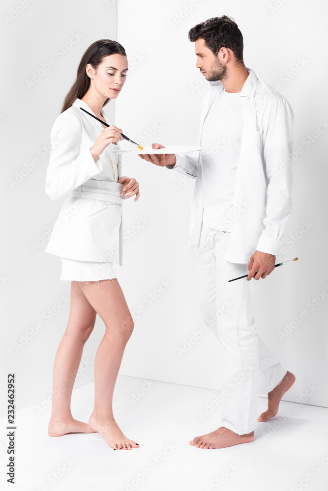 adult artists in total white posing with paintbrushes and palette