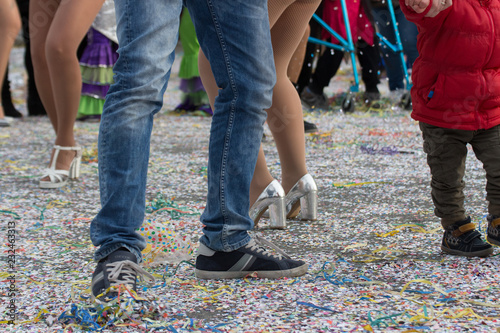 People walking over confetti in the street at Carnival