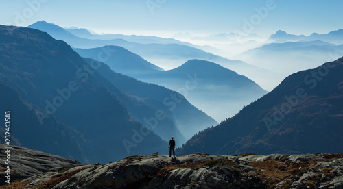Man looking at the foggy, blue layers of mountains. Near Chamonix, France.