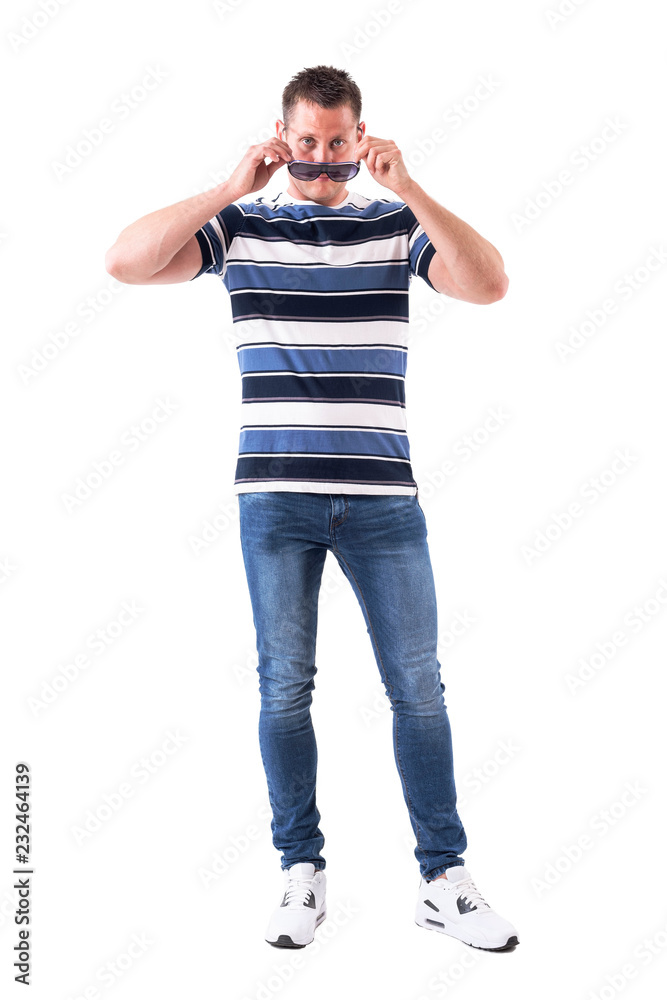 Serious confident adult man applying or taking off sunglasses with intense stare at camera. Full body isolated on white background. Serious confident adult man applying or taking off sunglasses with intense stare at camera. Full body isolated on white background.
