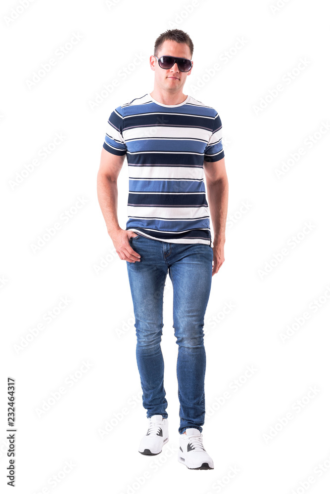 Confident macho serious man walking and approaching and looking at camera with sunglasses. Full body isolated on white background. Confident macho serious man walking and approaching and looking at camera with sunglasses. Full body isolated on white background.