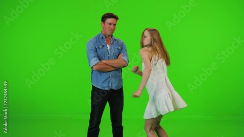 A woman dances around her date happily, trying to convince him to join. He doesn�t like the music and doesn�t join, over a green screen.