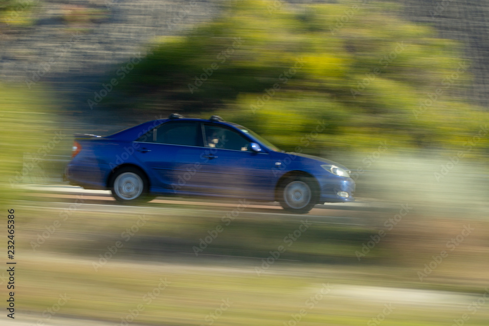 Motion blur of a blue car over the road
