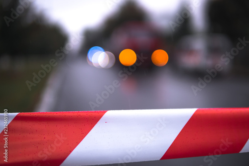 Red and White Lines of barrier tape on the background of firefighters and fire trucks at work. bokeh, selective focus, place for text, protects for No entry. photo