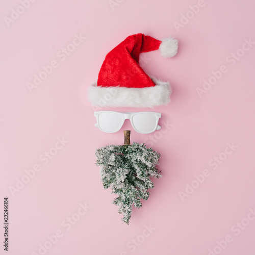 Santa Claus portrait with hipster sunglasses on pink background with copy space. Minimal flat lay Christmas theme. New year sale concept.