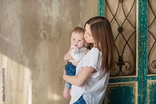 Happy Mothers Day. Adorable happy woman with baby posing in stylish modern studio decorations. Design element for card, poster, banner, and other use.