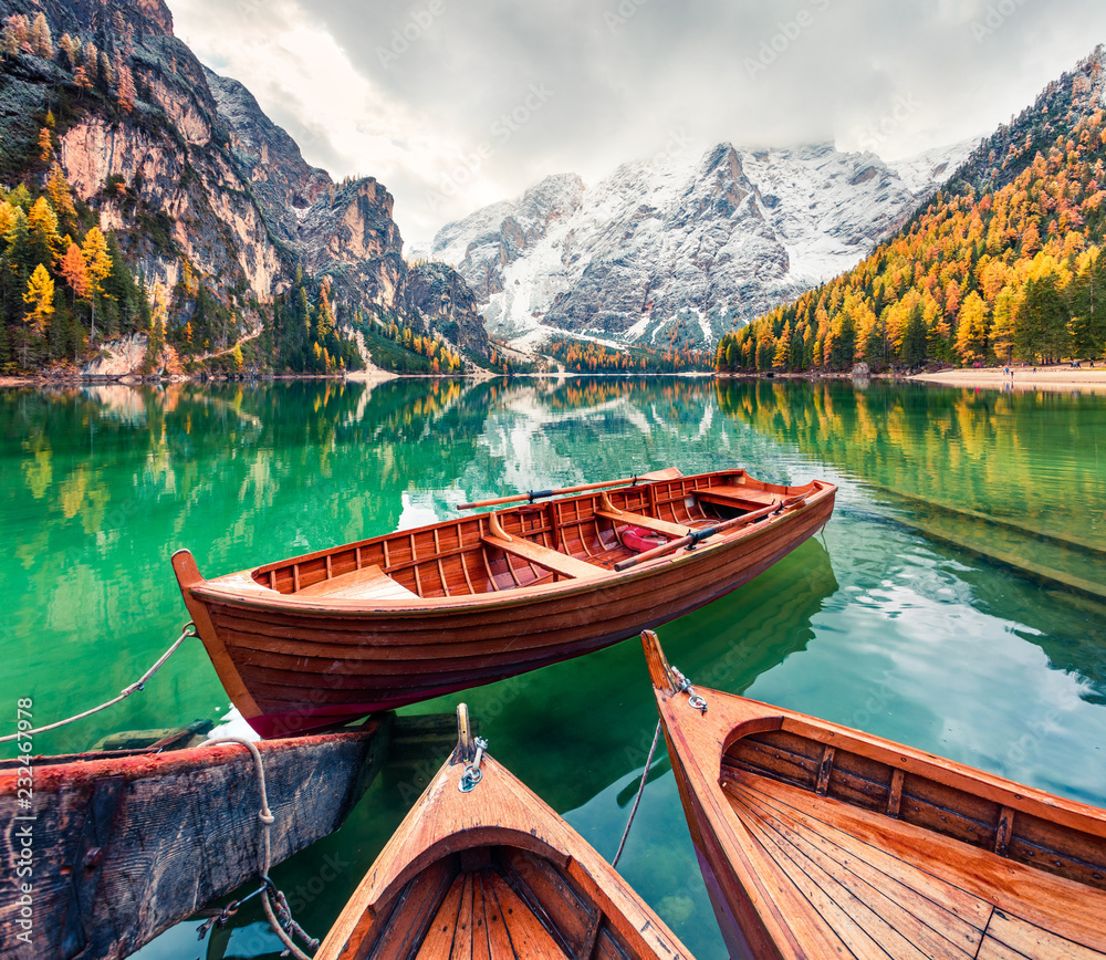 Pleasure boats on Braies Lakeand Seekofel mount on background. Colorful autumn morning in Italian Alps, Naturpark Fanes-Sennes-Prags, Dolomite, Italy, Europe. Traveling concept background.