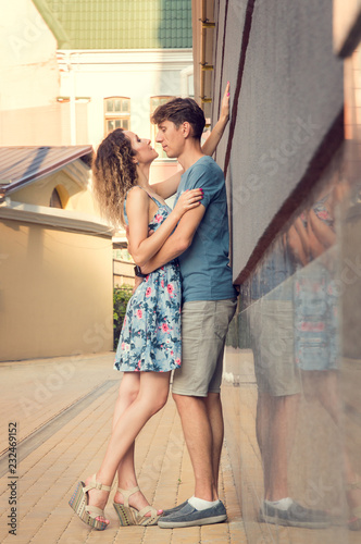 Romance. A man and a woman are entwined in a loving embrace. Sunlit courtyard in the background.