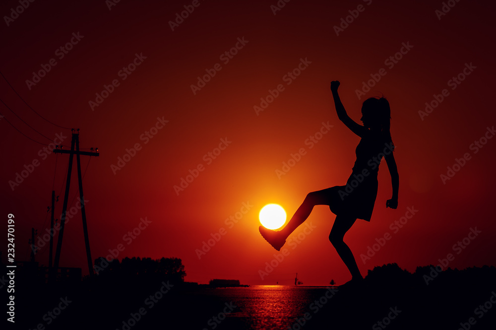 silhouette of girl on sunset background of the sky