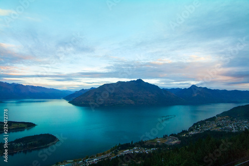 Evening panoramic view of Cecil Peak and Walter Peak above Lake Wakatipu and lakefront houses on hill from Queenstown gondola skyline, New Zealand
