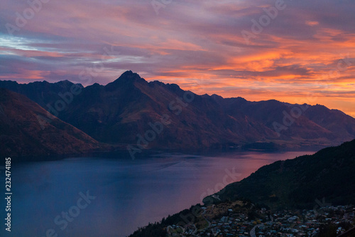 Southern alps mountains with colorful romantic sunset on cloudy sky background, reflection on the lake Wakatipu, Walter Peak Queenstown New Zealand view from the cable car in the city © Radoslav Cajkovic