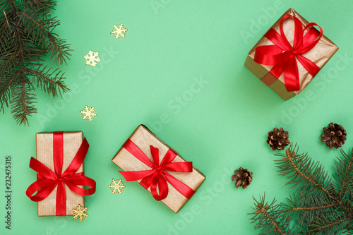 Gift boxes, fir tree branches with decorative snowflakes on green background
