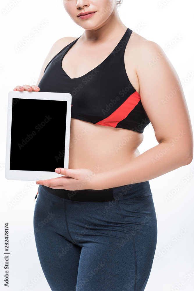 cropped shot of young overweight woman in sportswear holding digital tablet with blank screen isolated on white