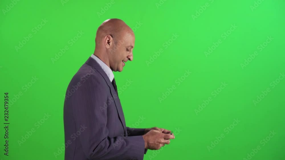 Businessman writing a text on his phone and gets some good news, kisses phone happily, wearing a suit. medium sideways shot over a green screen. Businessman writing a text on his phone and gets some good news, kisses phone happily, wearing a suit. medium sideways shot over a green screen.