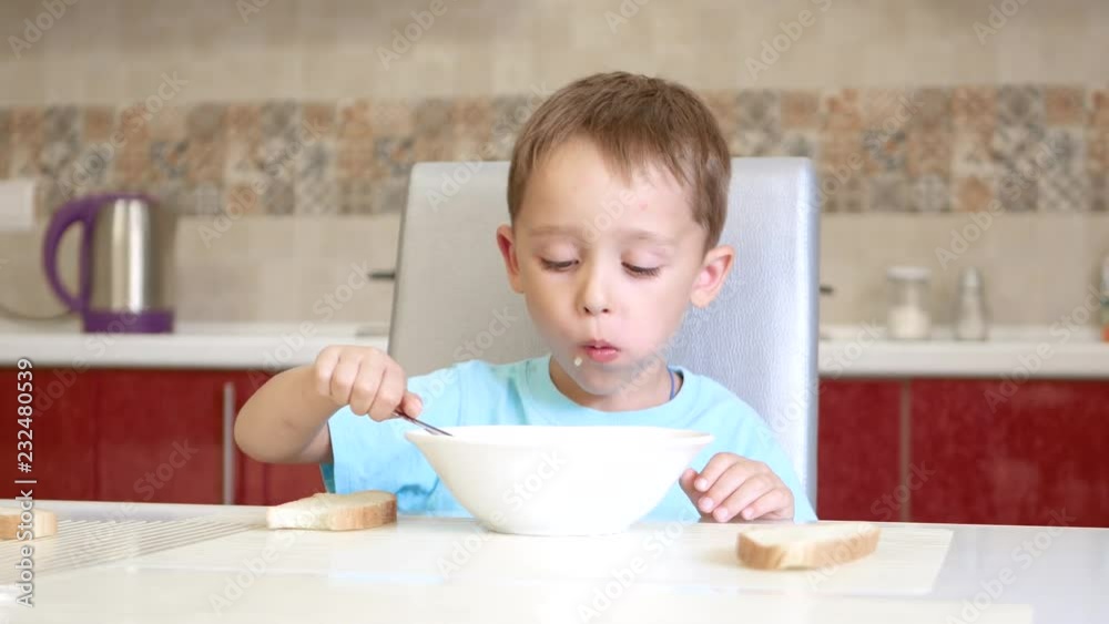 The child sits at the kitchen table, eats bread and soup. The child sits at the kitchen table, eats bread and soup.