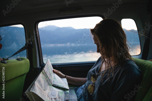 Young woman sitting on backseat in a car looking at map photo