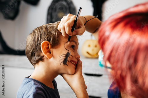 Mother painting her son's face for Halloween photo