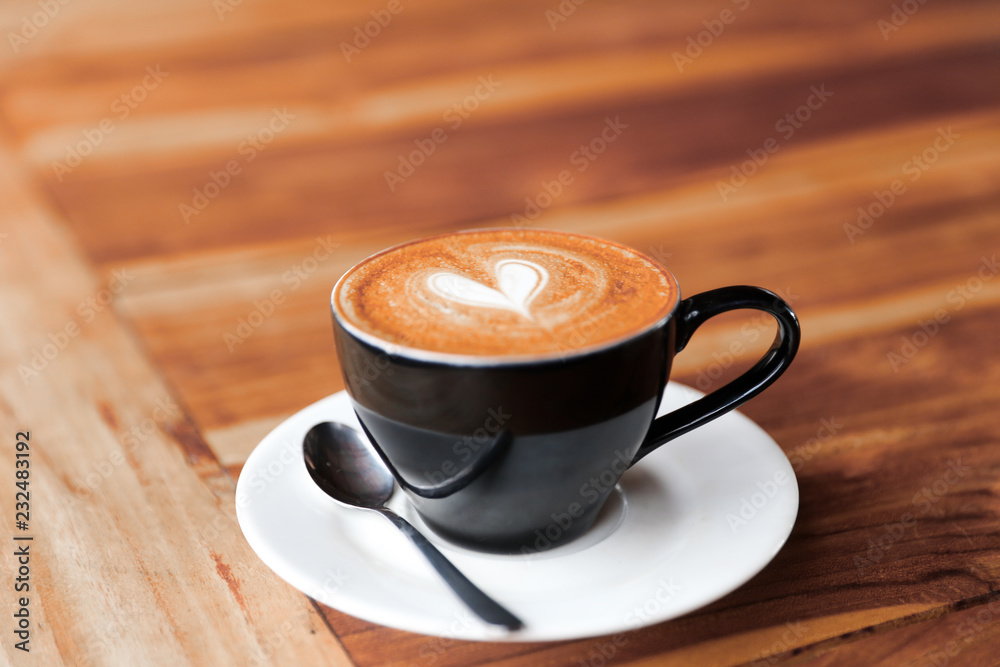 Fototapeta premium Cappuccino cup with heart latte art on wooden table background.