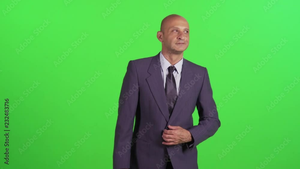 Businessman looking around, waves hello, walking towards camera, wearing a suit. Medium frontal shot over a green screen. Businessman looking around, waves hello, walking towards camera, wearing a suit. Medium frontal shot over a green screen.