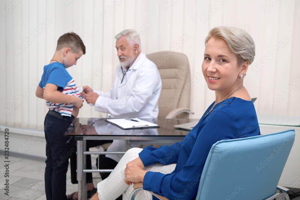 Obraz premium Mother smiling, waiting on doctor examining her son.