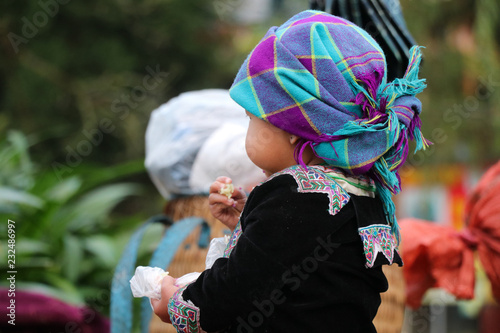 Hmong girl dressed in colorful hand-woven cloth in hand holding food at Lao Cai, Sapa Vietnam 21 October 2018