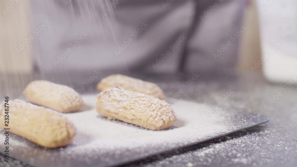 Crane shot. Close up hands of pastry chef sprinkling eclairs with powdered sugar Crane shot. Close up hands of pastry chef sprinkling eclairs with powdered sugar