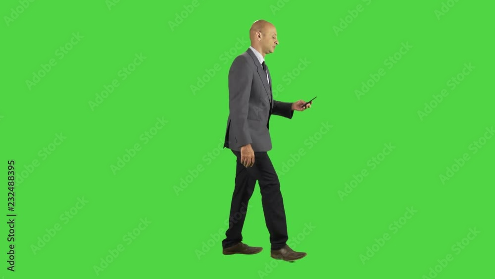 Businessman answers a phone call, cool and relaxed, talks and hangs, wearing a suit. full sideways shot over a green screen. Businessman answers a phone call, cool and relaxed, talks and hangs, wearing a suit. full sideways shot over a green screen.
