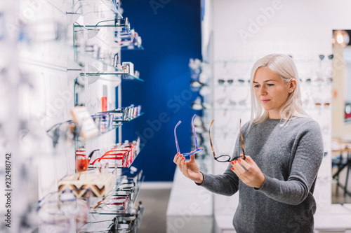 Woman comparing glasses at optic store.