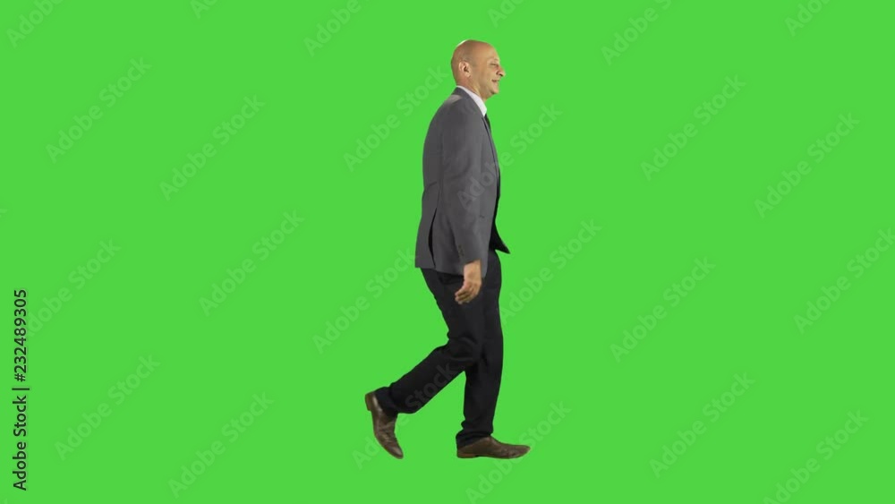 Businessman using an app while walking, happy and excited, wearing a suit. full sides shot over a green screen. Two takes. Businessman using an app while walking, happy and excited, wearing a suit. full sides shot over a green screen. Two takes.