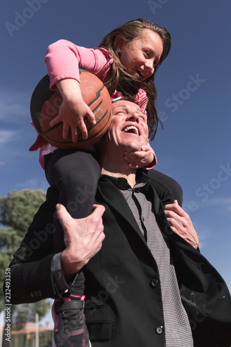 Smiling father carrying his daughter on shoulder