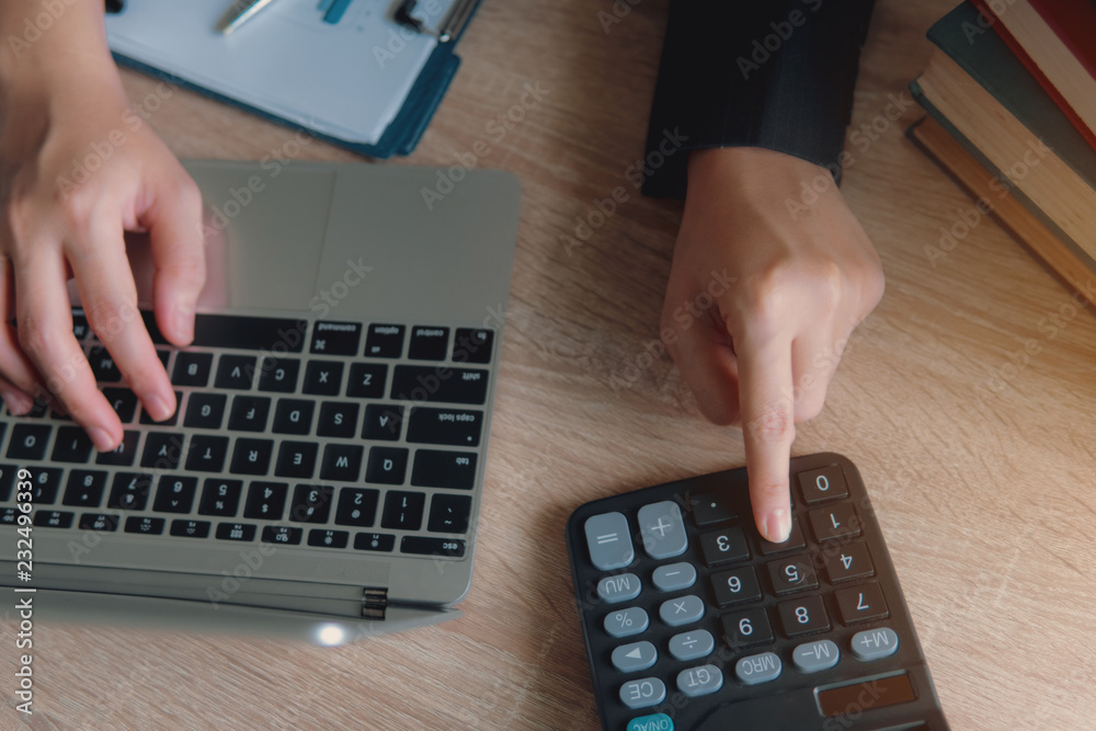 Business financial manager using calculator and laptop for analyzing finance graph data in office. successful concept. Business financial manager using calculator and laptop for analyzing finance graph data in office. successful concept.