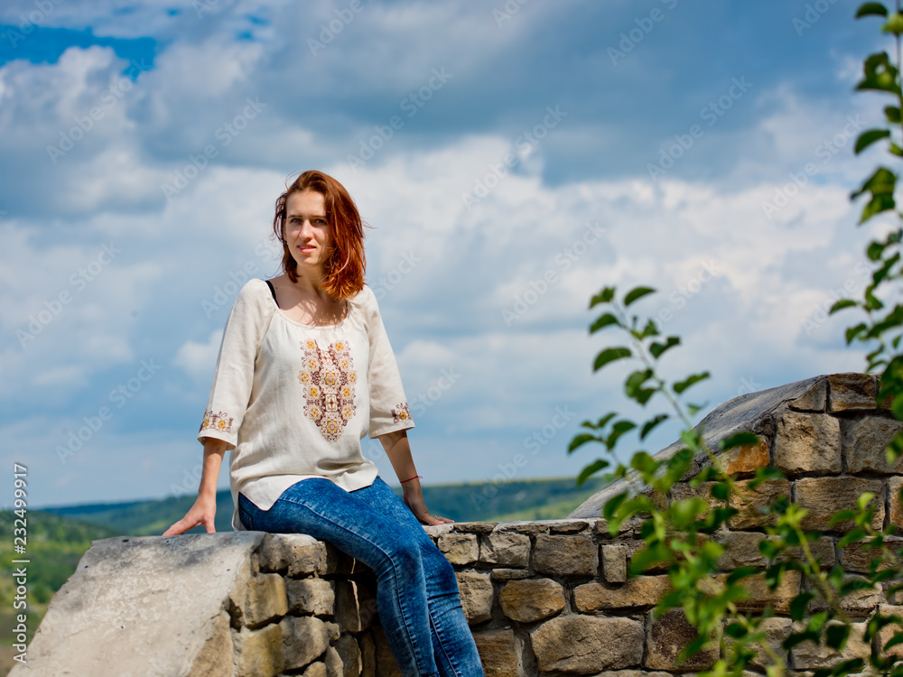 Beautiful young girl with red hair posing against nature background.