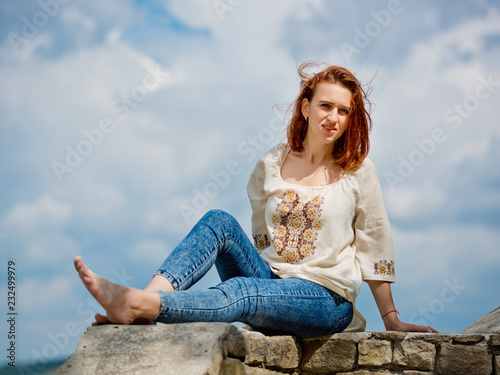Beautiful young girl with red hair posing against nature background.