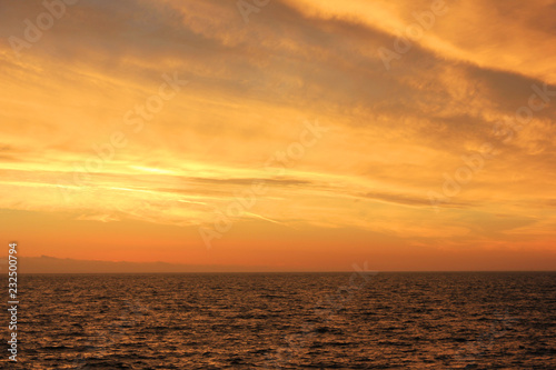 Sunset Sky Landscape Over Sea Water with Vibrant Orange Cloudscape. Scenic Empty Sky Background at Sunset or Sunrise, Dusk and Dawn Beautiful Skyline View with Still Water Perspective Panorama  © onajourney