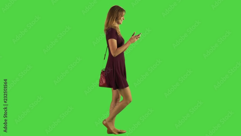 Young woman walking while texting. Happy. Full body shot over green screen. Two takes. Young woman walking while texting. Happy. Full body shot over green screen. Two takes.