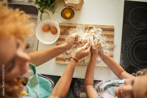Top view of female parent and child preparing b-day cake on kitchen table with baking ingredients.