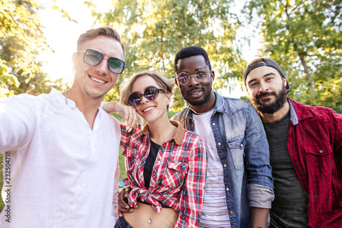 Diverse group of young adult people in cassual summer outfit gathering in summer park after their outdoor workout photo