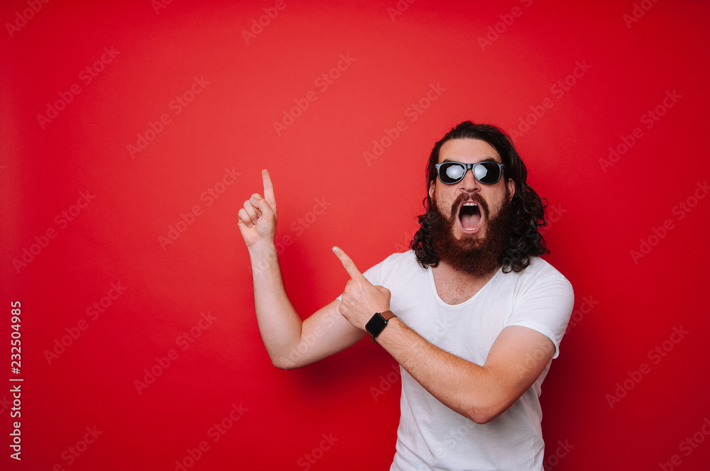 Excited man with beard pointing away at copyspace Excited man with beard pointing away at copyspace