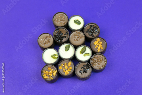 Chocolate candies on a colored background. Candies with different fillings laid out on a color table.