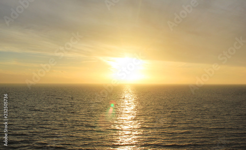 Sky Nature View of Sunset Over Calm Sea Water with Light Orange Cloudscape. Beautiful Sky Background at Sunset or Sunrise, Dusk or Dawn Panoramic Skyline View with Still Water on Summer Season Day © onajourney