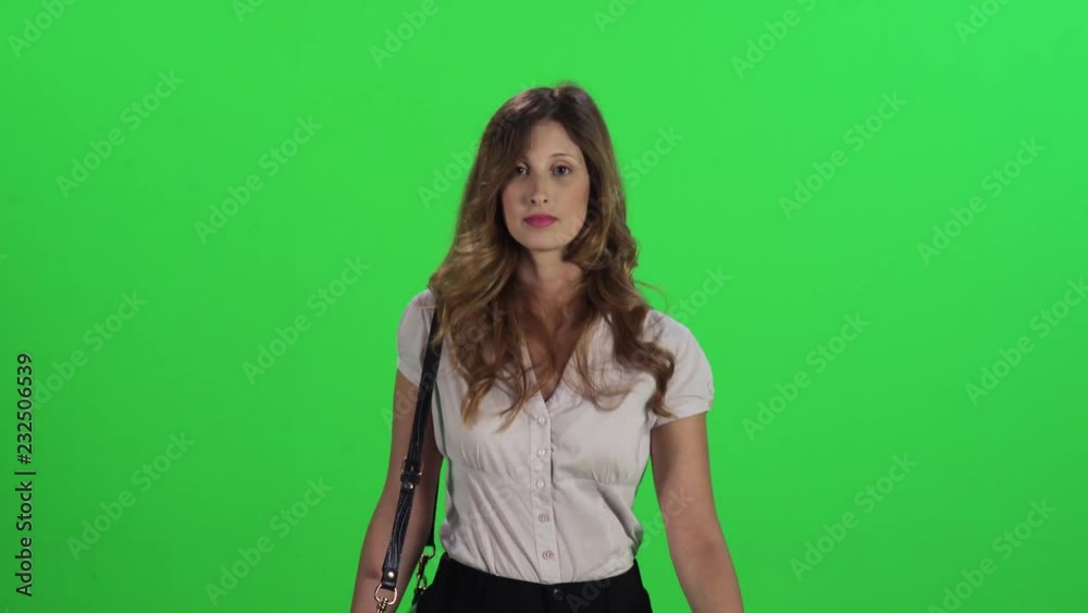 A young businesswoman walking fast in a medium frontal shot over a green screen, laughs and points into the lens. A young businesswoman walking fast in a medium frontal shot over a green screen, laughs and points into the lens.