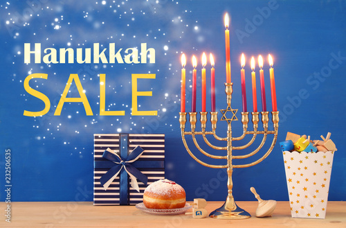 Image of jewish holiday Hanukkah background with traditional spinnig top, menorah (traditional candelabra) and burning candles.