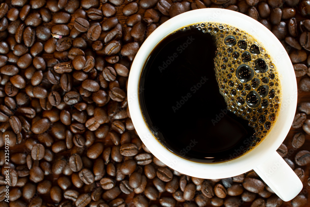Hot black coffee or Americano putting on arabica seeds at the background as for breakfast or break drinks concept. Hot black coffee or Americano putting on arabica seeds at the background as for breakfast or break drinks concept.