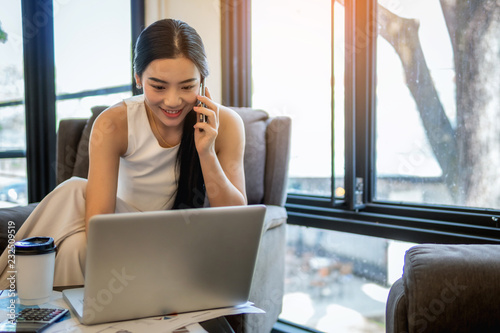 young business woman working at a coffee shop with a laptop. She drinking a coffee and use mobile phone for contact customer. Free Download young business woman working at a coffee shop with a laptop. She drinking a coffee and use mobile phone for contact customer. - GFXLoad